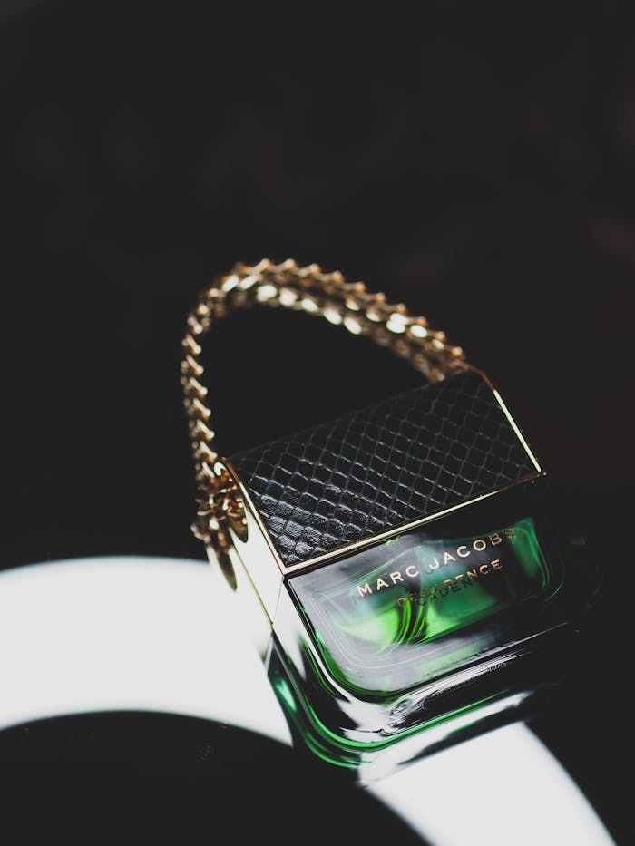 Services Elegant perfume bottle with chain detail on a sleek black surface, perfect for fashion and cosmetics.