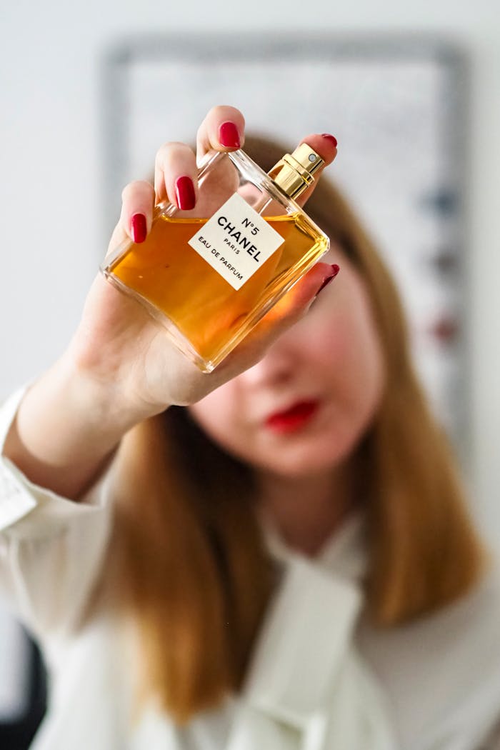A close-up of a woman holding a Chanel N°5 Eau de Parfum bottle with a blurred background.